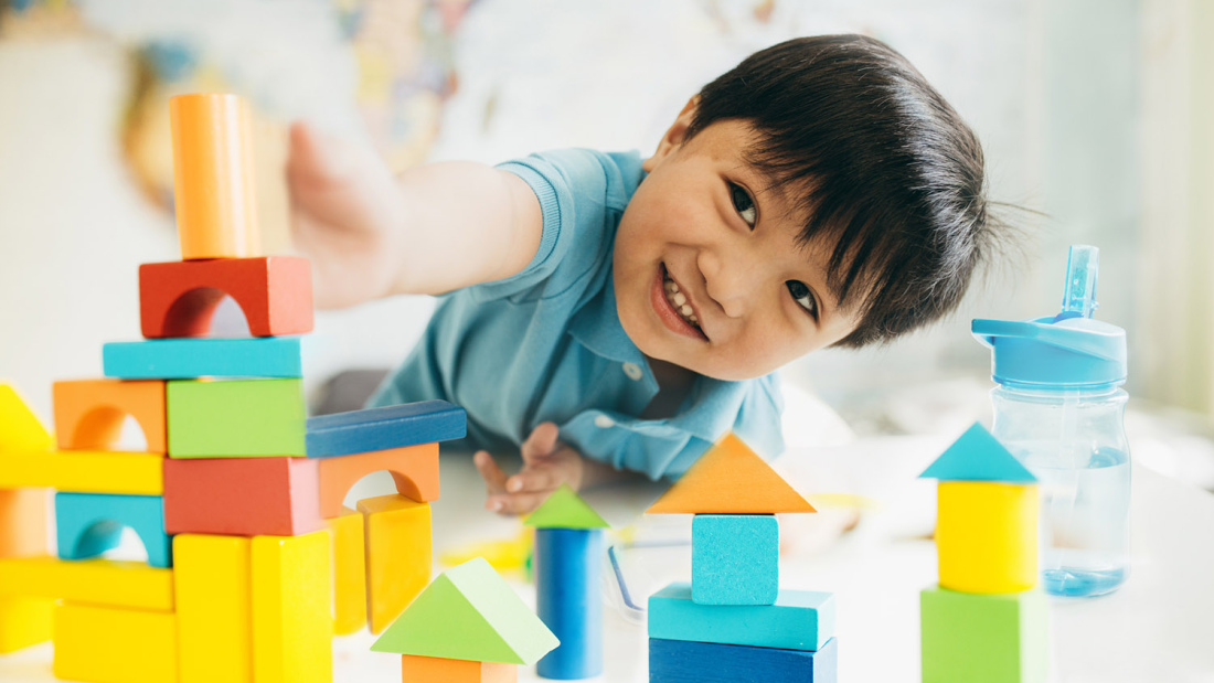 Young child smiling and playing with blocks