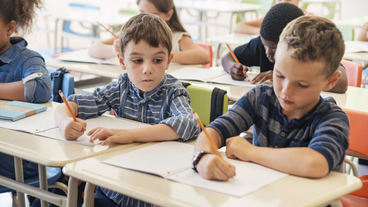 A young boy looks at his classmate's work