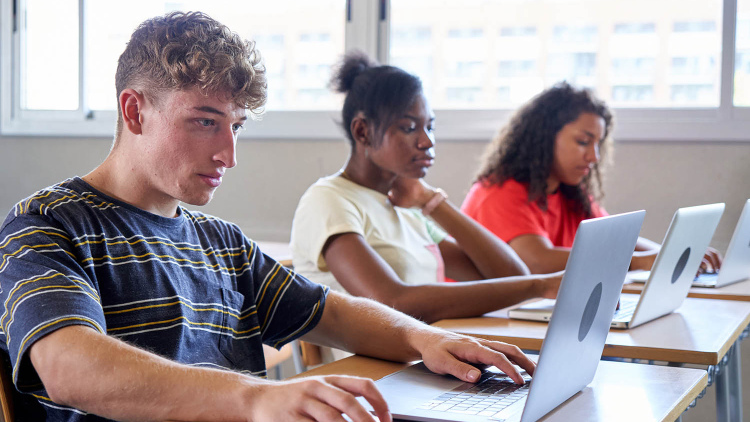Three students on laptops taking test