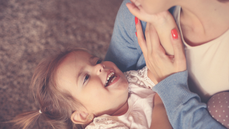 Young girl smiles up at her mother