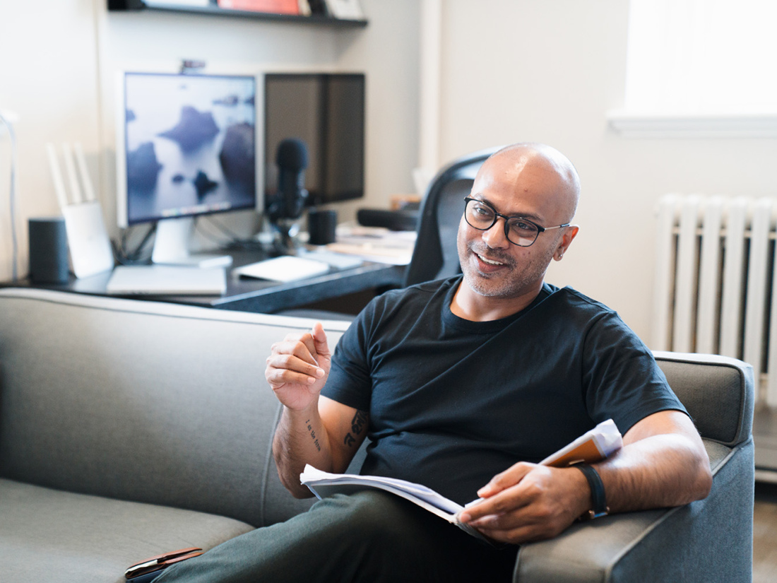 Man sitting on sofa with book with hand lifted